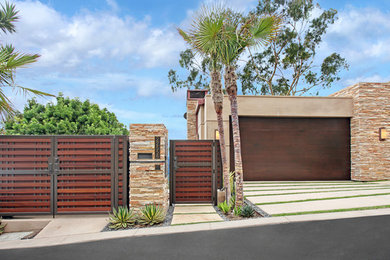 This is an example of a large contemporary three-storey stucco beige house exterior in Orange County with a flat roof.