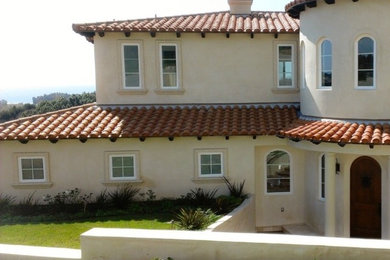 Example of a large southwest beige two-story exterior home design in Los Angeles with a hip roof