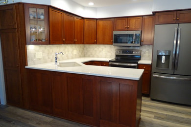 Inspiration for a mid-sized timeless u-shaped laminate floor and multicolored floor enclosed kitchen remodel in Other with an undermount sink, shaker cabinets, medium tone wood cabinets, quartz countertops, beige backsplash, ceramic backsplash, black appliances, white countertops and a peninsula