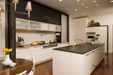 Inspiration for a large contemporary galley dark wood floor eat-in kitchen remodel in New Orleans with an undermount sink, flat-panel cabinets, white cabinets, granite countertops, white backsplash, subway tile backsplash, stainless steel appliances and an island