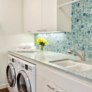 サンフランシスコのコンテンポラリースタイルのおしゃれなランドリールーム (ダブルシンク、フラットパネル扉のキャビネット、白いキャビネット、テラゾーカウンター、左右配置の洗濯機・乾燥機、ターコイズのキッチンカウンター、白い壁) の写真