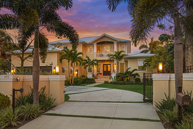 Large island style beige two-story wood exterior home photo in Tampa with a metal roof