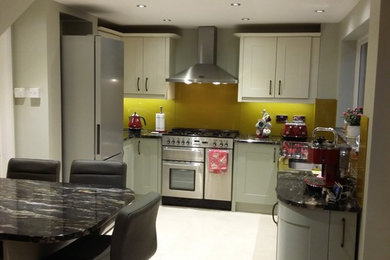 Inspiration for a mid-sized contemporary u-shaped eat-in kitchen in Other with an undermount sink, shaker cabinets, green cabinets, granite benchtops, yellow splashback, glass sheet splashback, stainless steel appliances, ceramic floors and with island.