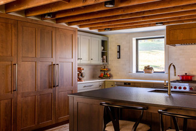 Example of a large farmhouse l-shaped medium tone wood floor, brown floor and exposed beam open concept kitchen design in New York with an undermount sink, shaker cabinets, medium tone wood cabinets, granite countertops, white backsplash, ceramic backsplash, paneled appliances, an island and black countertops