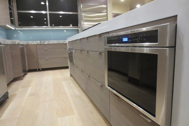 Inspiration for a huge modern u-shaped light wood floor eat-in kitchen remodel in San Francisco with a double-bowl sink, flat-panel cabinets, gray cabinets, quartz countertops, blue backsplash, glass sheet backsplash, stainless steel appliances and an island