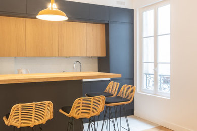 Exemple d'une cuisine ouverte encastrable et noire et bois tendance en L de taille moyenne avec un évier encastré, un placard à porte plane, des portes de placard noires, un sol en carrelage de céramique, îlot et un sol blanc.