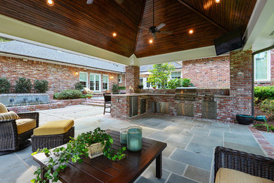 Mid-sized elegant backyard stone patio kitchen photo in Other
