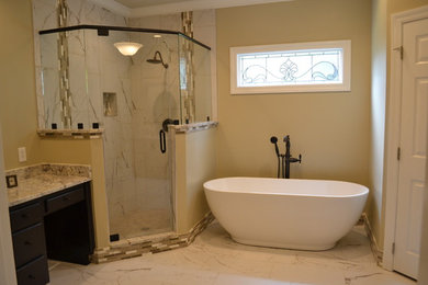 This is an example of a large transitional master bathroom in Other with raised-panel cabinets, dark wood cabinets, a freestanding tub, a corner shower, multi-coloured tile, matchstick tile, beige walls, marble floors, an undermount sink, granite benchtops, white floor, a hinged shower door and beige benchtops.