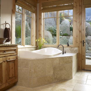 Réalisation d'une salle de bain tradition avec une vasque, une baignoire posée et du carrelage en travertin.