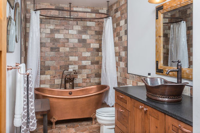 Inspiration for a mid-sized country 3/4 bathroom in Other with shaker cabinets, medium wood cabinets, a claw-foot tub, multi-coloured tile, white walls, a vessel sink, a two-piece toilet, ceramic floors, engineered quartz benchtops and a shower curtain.