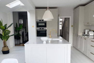 Foto på ett mellanstort funkis vit kök och matrum, med en köksö, svarta vitvaror, en nedsänkt diskho och vitt golv