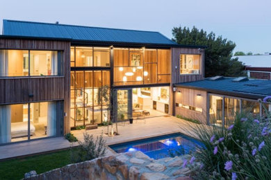 Large trendy black two-story wood house exterior photo in Other with a shed roof and a metal roof
