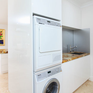 Design ideas for a contemporary utility room in Brisbane with onyx worktops, a stacked washer and dryer, beige floors and multicoloured worktops.