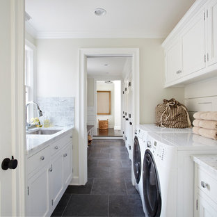 ニューヨークのトラディショナルスタイルのおしゃれなランドリールーム (白いキャビネット、スレートの床、黒い床、白いキッチンカウンター) の写真