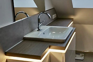 Großes Modernes Badezimmer mit flächenbündigen Schrankfronten, weißen Schränken, grauen Fliesen, weißer Wandfarbe, Einbauwaschbecken, grauem Boden, brauner Waschtischplatte, Einzelwaschbecken und schwebendem Waschtisch in Köln