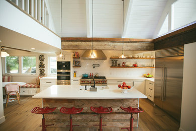 Mid-sized country u-shaped light wood floor open concept kitchen photo in Orange County with a farmhouse sink, shaker cabinets, white cabinets, stainless steel appliances and an island