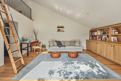 Example of a large arts and crafts loft-style light wood floor, beige floor and vaulted ceiling family room library design in Los Angeles with white walls, no fireplace and a wall-mounted tv