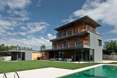 Example of a large trendy brown three-story wood exterior home design in Madrid with a mixed material roof