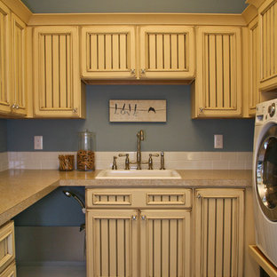 Design ideas for a large traditional u-shaped utility room in Grand Rapids with a built-in sink, recessed-panel cabinets, yellow cabinets, composite countertops, blue walls, slate flooring and a side by side washer and dryer.