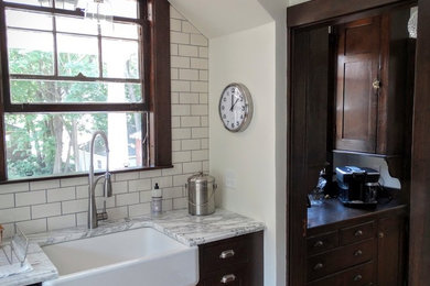 Inspiration for a mid-sized craftsman medium tone wood floor eat-in kitchen remodel in Other with a farmhouse sink, shaker cabinets, dark wood cabinets, marble countertops, white backsplash and subway tile backsplash