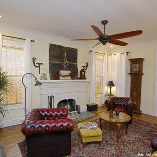 Modelo de salón para visitas cerrado, mediterráneo, pequeño, con paredes amarillas, suelo de madera en tonos medios, chimenea tradicional, marco de chimenea de baldosas y/o azulejos y televisor colgado en la pared