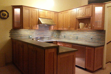 Example of a large u-shaped light wood floor kitchen design in San Francisco with an undermount sink, flat-panel cabinets, medium tone wood cabinets, quartzite countertops, green backsplash, stone tile backsplash, stainless steel appliances and a peninsula