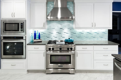 Large transitional u-shaped marble floor eat-in kitchen photo in Dallas with an island, a farmhouse sink, shaker cabinets, white cabinets, quartz countertops, glass tile backsplash, stainless steel appliances and blue backsplash
