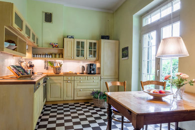 Geschlossene Rustikale Küche ohne Insel in L-Form mit Arbeitsplatte aus Holz, Küchenrückwand in Weiß, Rückwand aus Keramikfliesen, schwarzen Elektrogeräten, Zementfliesen für Boden und brauner Arbeitsplatte in Köln