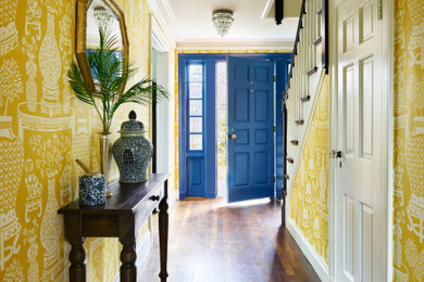 На фото: большая узкая прихожая в классическом стиле с желтыми стенами, паркетным полом среднего тона, одностворчатой входной дверью, синей входной дверью, коричневым полом и обоями на стенах