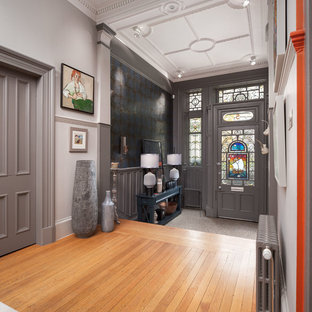Imagen de distribuidor bohemio con paredes grises, suelo de madera en tonos medios, puerta simple, puerta gris y suelo marrón