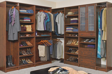 Photo of a large traditional gender-neutral dressing room in Other with recessed-panel cabinets, dark wood cabinets, carpet and grey floor.