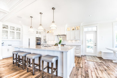 Large transitional l-shaped medium tone wood floor eat-in kitchen photo in Other with an undermount sink, shaker cabinets, white cabinets, quartzite countertops, white backsplash, subway tile backsplash, stainless steel appliances and an island