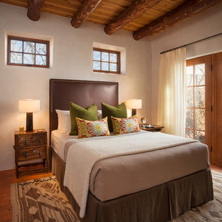 Idée de décoration pour une chambre d'amis sud-ouest américain avec un mur beige, un sol en brique et aucune cheminée.