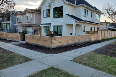 This is an example of a mid-sized modern full sun front yard concrete paver and wood fence formal garden in Vancouver.