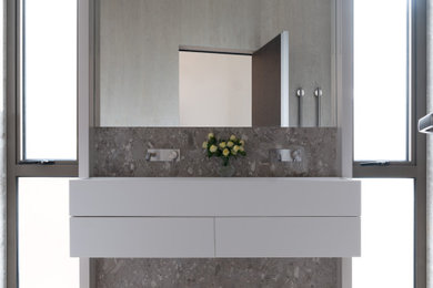 Photo of a medium sized modern grey and cream shower room bathroom in London with flat-panel cabinets, white cabinets, a walk-in shower, a wall mounted toilet, beige tiles, travertine tiles, beige walls, ceramic flooring, a wall-mounted sink, terrazzo worktops, beige floors, an open shower, beige worktops, a wall niche, double sinks and a floating vanity unit.