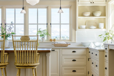 Design ideas for a large traditional u-shaped kitchen in Seattle with a farmhouse sink, flat-panel cabinets, white cabinets, quartz benchtops, dark hardwood floors, with island and brown floor.