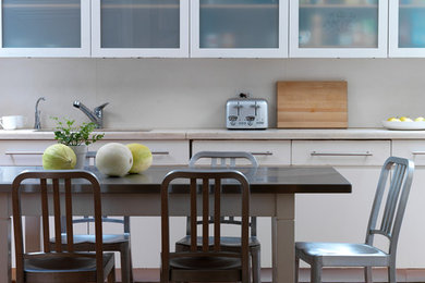 Example of a trendy dark wood floor eat-in kitchen design in New York with an undermount sink, glass-front cabinets and white cabinets