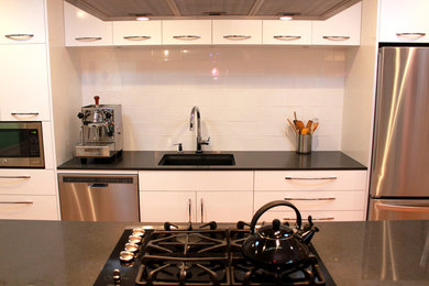 Inspiration for a mid-sized contemporary medium tone wood floor eat-in kitchen remodel in San Francisco with flat-panel cabinets, white cabinets, granite countertops, white backsplash, ceramic backsplash, stainless steel appliances and an island
