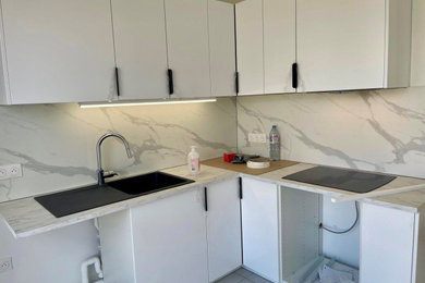 Exemple d'une cuisine moderne en L fermée et de taille moyenne avec un évier encastré, un placard à porte plane, des portes de placard blanches, un plan de travail en stratifié, une crédence blanche, une crédence en bois, un électroménager noir, un sol en carrelage de céramique, aucun îlot, un sol blanc et un plan de travail blanc.