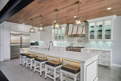 Huge transitional l-shaped porcelain tile, gray floor and wood ceiling open concept kitchen photo in Chicago with an undermount sink, glass-front cabinets, white cabinets, quartz countertops, gray backsplash, glass tile backsplash, stainless steel appliances, an island and white countertops