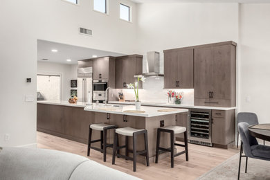 Example of a large trendy galley light wood floor eat-in kitchen design in Phoenix with an undermount sink, flat-panel cabinets, medium tone wood cabinets, quartz countertops, white backsplash, subway tile backsplash, stainless steel appliances, an island and white countertops