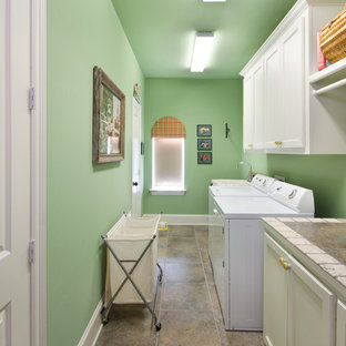 ニューオリンズの中サイズのトラディショナルスタイルのおしゃれな洗濯室 (落し込みパネル扉のキャビネット、白いキャビネット、タイルカウンター、緑の壁、左右配置の洗濯機・乾燥機) の写真
