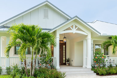Ejemplo de fachada de casa blanca y gris tropical de una planta con revestimiento de estuco, tejado a dos aguas, tejado de metal y panel y listón