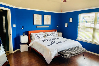 Foto de dormitorio principal y abovedado minimalista grande con paredes azules, suelo laminado y suelo marrón