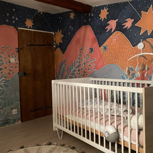 Cette photo montre une petit chambre de bébé neutre avec un mur multicolore, sol en stratifié, un sol beige, un plafond en poutres apparentes et du papier peint.