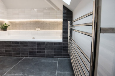 This is an example of a medium sized contemporary ensuite wet room bathroom in Other with flat-panel cabinets, white cabinets, a built-in bath, a one-piece toilet, white tiles, white walls, a wall-mounted sink, grey floors, an open shower, white worktops, a feature wall, a single sink and a floating vanity unit.
