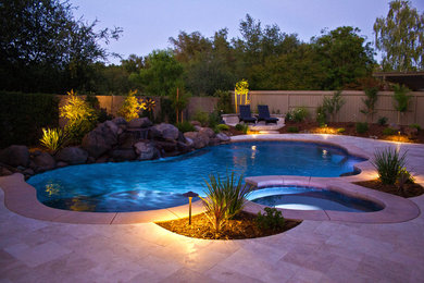 This is an example of a large traditional backyard custom-shaped natural pool in Sacramento with a hot tub and natural stone pavers.