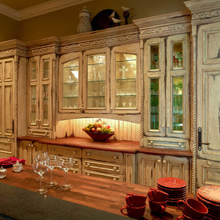 Photo of a mid-sized mediterranean galley kitchen pantry in Denver with wood benchtops, medium hardwood floors, an undermount sink, raised-panel cabinets, distressed cabinets, panelled appliances, no island and brown floor.