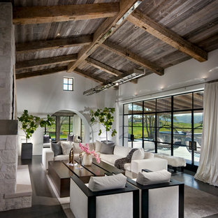 Expansive mediterranean open plan living room in Orange County with medium hardwood flooring, a two-sided fireplace and a stone fireplace surround.