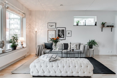 This is an example of a mid-sized scandinavian formal open concept living room in Gothenburg with white walls, light hardwood floors, no fireplace and no tv.